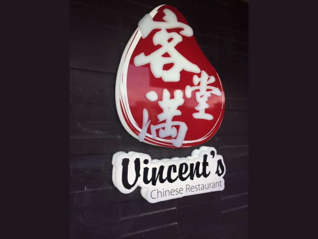 Restaurant logo sign with raised lettering on a dark wall
